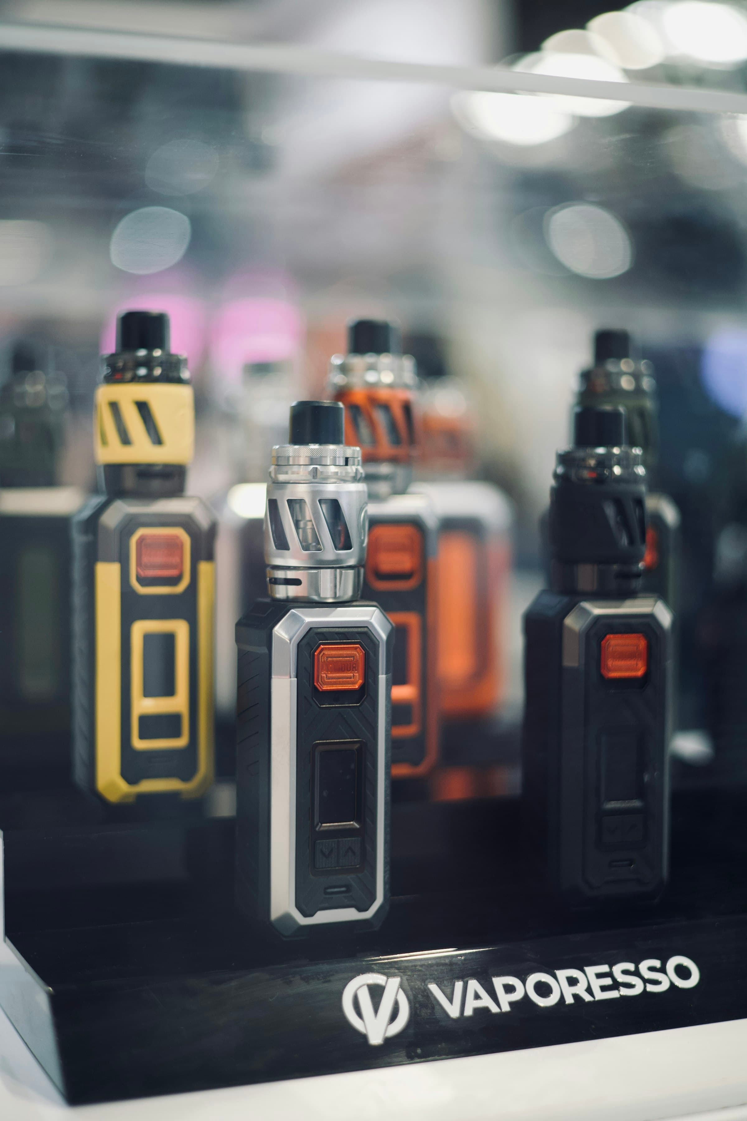 A glass display case holding several different vape pod kits and mods from various manufacturers side by side