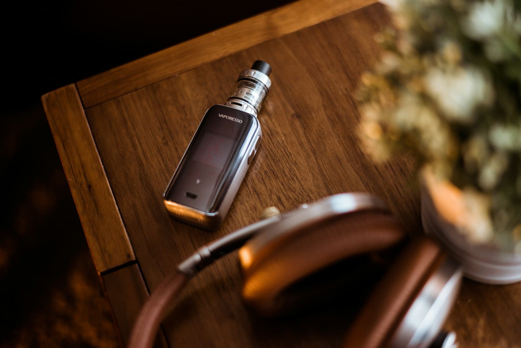 A premium Vaporesso pod mod kit resting on a dark wood surface, softly lit