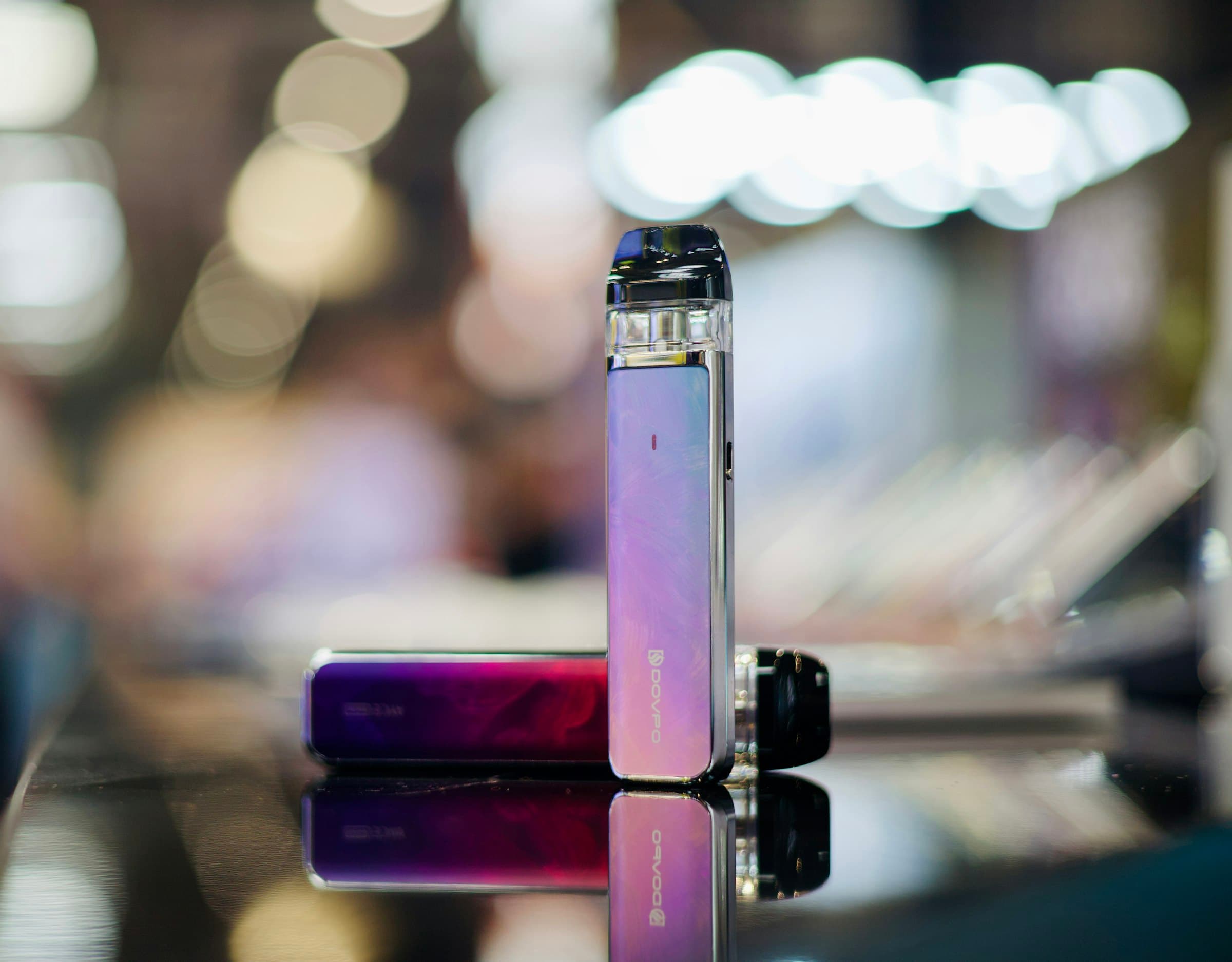 Two different pod vape kits placed side by side on a table, photographed close up