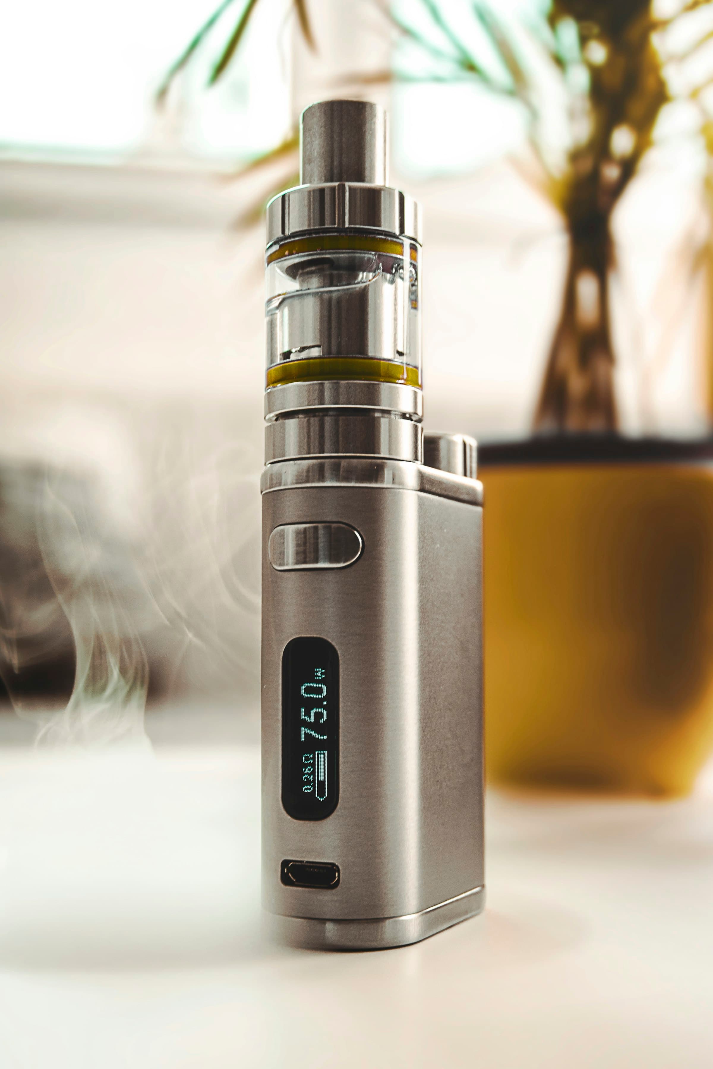 A single matte grey pod vape device photographed close up against a softly lit smoke backdrop