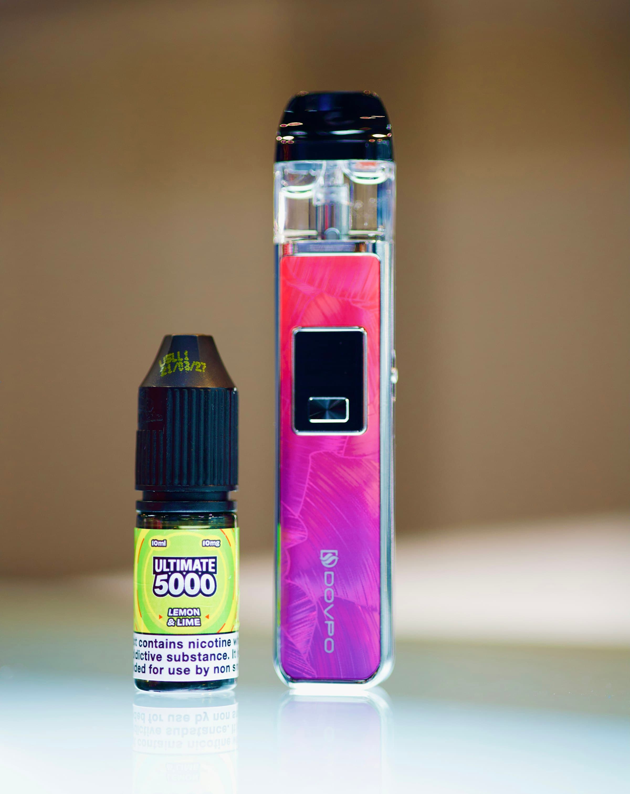 A 10ml nic salt e-liquid bottle showing its nicotine strength on the label, standing next to a pod vape device